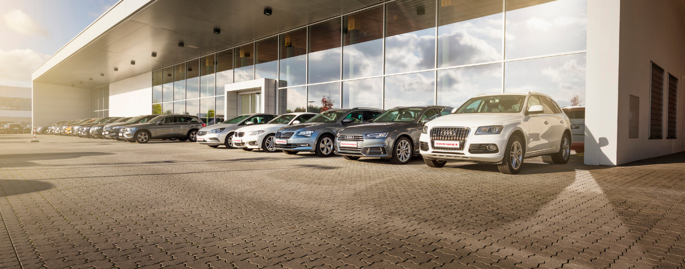 Verschiedene Autos stehen vor einem Glasgeb&auml;ude